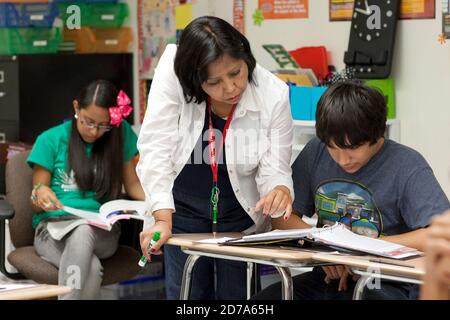 Une enseignante hispanique travaille en tête-à-tête avec un étudiant pendant la classe à l'école secondaire Achieve Early College sur le campus du South Texas College. L'école, qui fait partie du très réputé district scolaire McAllen dans le sud du Texas, à la frontière entre les États-Unis et le Mexique, compte près de 500 3/4 élèves, dont près de 100 000 proviennent de familles économiquement défavorisées. Banque D'Images