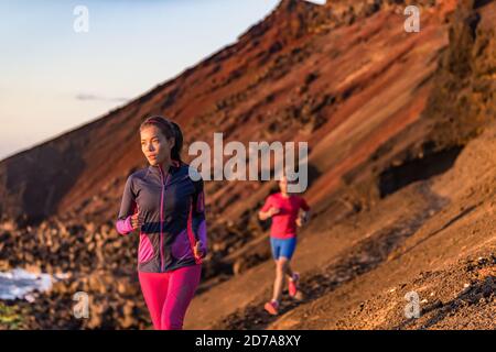 Couple sportif s'entraîner ensemble dans un paysage de montagne en plein air. Femme asiatique coureuse sur le sentier avec l'homme en arrière-plan. Sportifs Banque D'Images