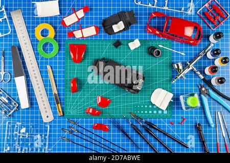 vue de bureau depuis le dessus de l'assemblage et de la peinture d'un modèle rétro rouge voiture concept arrière-plan. outils de modélisation aérographe pistolet pièce de kit de peinture Banque D'Images