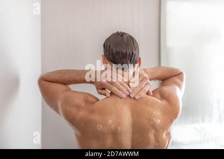 Homme prenant une douche se lavant les cheveux dans le bain à remous de luxe. Une jeune personne qui se montre en contact avec l'arrière du cou à la maison. Soins du corps beauté masculine Banque D'Images