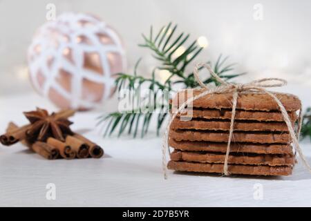 Ambiance de l'Avent et de Noël, spéculoos empilés avec un ruban d'emballage attaché, décoré sur une table en bois blanc dans le fond d'un boule de noël blanc Banque D'Images