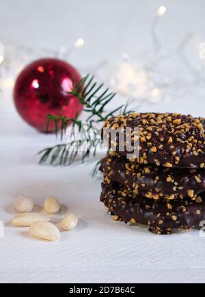 L'arrivée et l'ambiance de Noël, Elisenlebkuchen avec glaçage au chocolat et noisettes, sur une table en bois blanc à l'arrière-plan une boule de noël rouge Banque D'Images