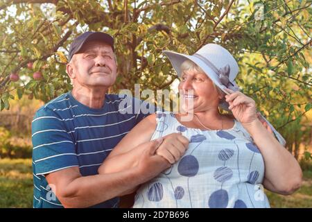 Photo authentique en plein air d'un couple vieillissant s'amusant dans le jardin et béni avec amour. Au cours de leur jeu, l'homme essaie d'embrasser son partenaire et elle l'est Banque D'Images