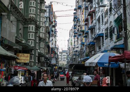 Yangon, Myanmar - 30 décembre 2019 : la vie quotidienne se déroule dans une rue étroite du centre-ville, avec des voitures garées et des piétons qui marchent Banque D'Images