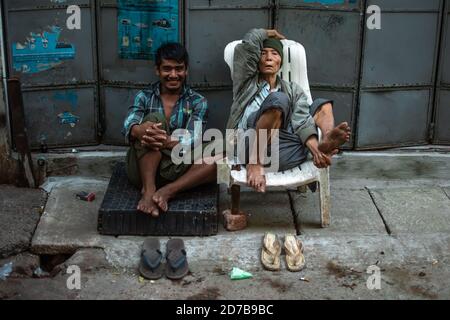 Yangon, Myanmar - 30 décembre 2019 : Portrait de deux birmans locaux assis sur le côté de la route dans le centre-ville de Yangon/Rangoon Banque D'Images