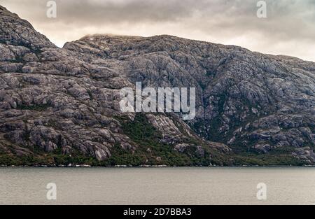Canal de Sarmiento, Chili - 11 décembre 2008 : glacier et fjord Amalia. Gros plan des falaises rocheuses grises et des rochers de l'île avec un feuillage vert à Banque D'Images