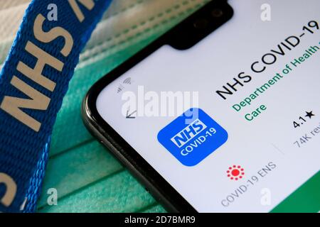 Application NHS COVID-19 vue dans Play Store sur l'écran du smartphone à côté des masques viraux et du cordon NHS. Banque D'Images