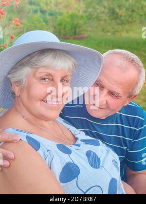 Photo authentique en plein air d'un couple vieillissant s'amusant dans le jardin et béni avec amour. Au cours de leur jeu, l'homme essaie d'embrasser son partenaire et elle l'est Banque D'Images