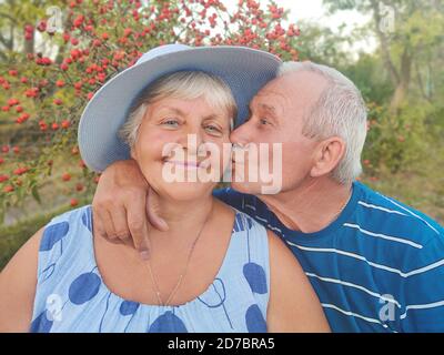 Photo authentique en plein air d'un couple vieillissant s'amusant dans le jardin et béni avec amour. Au cours de leur jeu, l'homme essaie d'embrasser son partenaire et elle l'est Banque D'Images