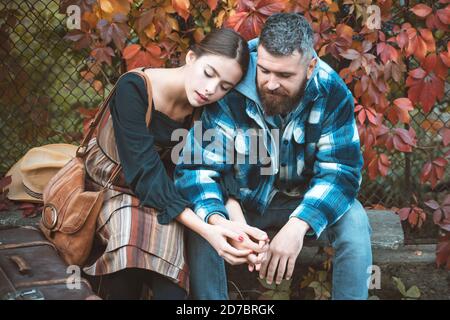 Une fille et un gars barbu ou des amoureux heureux sur une date tiennent les mains. Concept de datation et d'amour d'automne. Couple amoureux assis près du mur avec des feuilles de lierre. Taille basse Banque D'Images