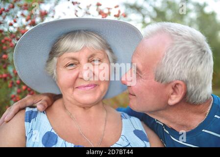 Photo authentique en plein air d'un couple vieillissant s'amusant dans le jardin et béni avec amour. Au cours de leur jeu, l'homme essaie d'embrasser sa femme et elle est smi Banque D'Images