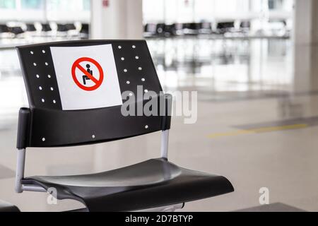 Vider la salle d'attente à un aéroport pendant la pandémie COVID-19 avec signes sociaux de distanciation sur les chaises Banque D'Images