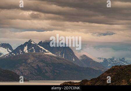 Canal de Sarmiento, Chili - 11 décembre 2008 : glacier et fjord Amalia. Le paysage nuageux brun et gris couvre une partie des sommets enneigés des montagnes. Canal argent avec Banque D'Images