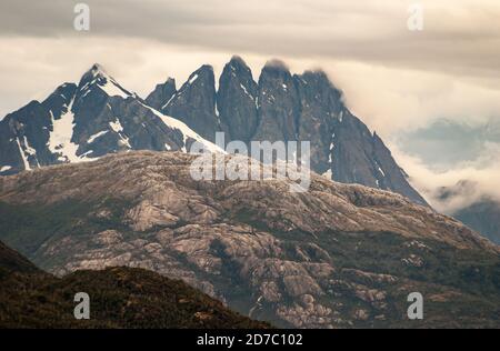 Canal de Sarmiento, Chili - 11 décembre 2008 : glacier et fjord Amalia. Sommets de montagne noirâtre avec de la neige partiellement couverte par un paysage de nuages brunâtre. Marron Banque D'Images