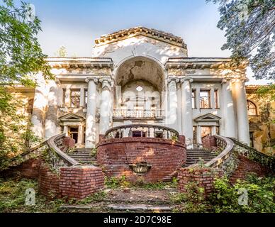 Bâtiment délabré abandonné dans le vieux parc. Escaliers, colonnes et balustrade. Seule la façade surcultivée de forêt est restée. Exemple de Banque D'Images