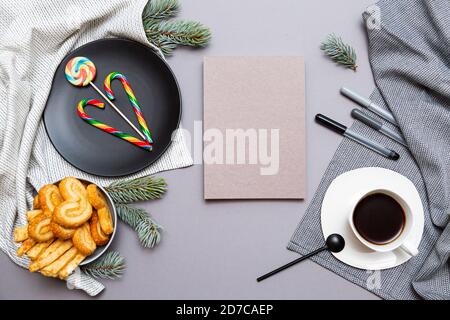 Bloc-notes, sucettes, biscuits, branches de sapin et une tasse de café sur fond gris. Liste de souhaits de Noël. Concept Noël et nouvel an Banque D'Images