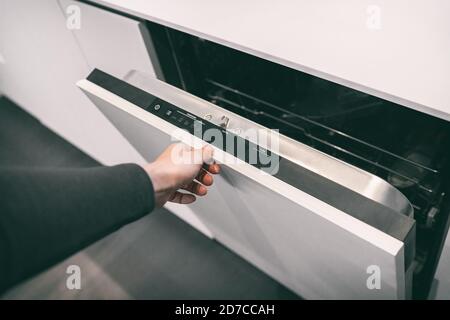 Femme ouvrant panneau lave-vaisselle intégré personnalisé dans cuisine moderne maison design intérieur tendance. Laver la vaisselle à la maison Banque D'Images