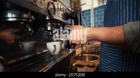 Un barista masculin prépare du café pour les clients dans un restaurant branché Banque D'Images