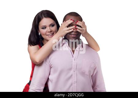 Couple multiracial amoureux. Famille de race mixte. Couple interracial isolé sur fond blanc. Femme souriante garde les yeux d'homme surpris couverts. Banque D'Images