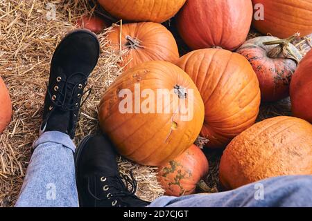 Vue de dessus du sabot sur le marché agricole sur le foin. Jambes en gros plan en Jean et chaussures dans le décor de Noël et d'Halloween Banque D'Images