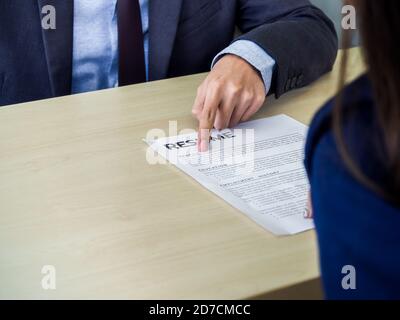 Le doigt de l'homme d'affaires pointant sur son profil sur le CV papier sur bureau avec espace de copie. Entrevue d'emploi et concept d'emploi. Banque D'Images