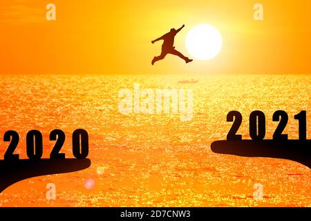Silhouette de jeune homme sautant entre 2020 et 2021 ans avec beau coucher de soleil sur la mer. Banque D'Images