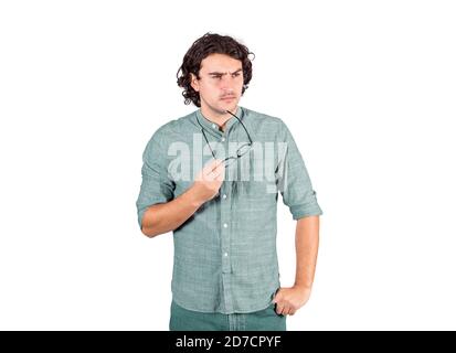 Un jeune homme confus, long style de cheveux bouclés, tient des lunettes dans sa main, geste réfléchi, en regardant de côté suspect isolé sur fond blanc. Pu Banque D'Images