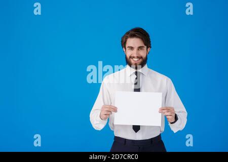 Homme d'affaires dans une chemise et cravate sur un fond bleu. Un jeune barbu tient un espace de copie papier pour le texte Banque D'Images