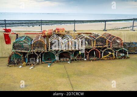 Des casiers à crabe ou homard empilés sur l'Esplanade, où les bateaux de pêche sont stationnés à Redcar North Yorkshire UK Banque D'Images