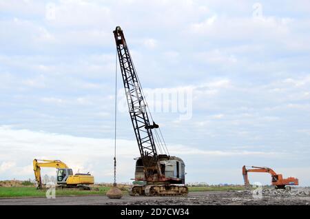 De grandes grues sur chenilles pelle à benne traînante ou avec un métal lourd boulet sur un câble en acier. Wrecking balles sur les chantiers de construction. Démontage et dem Banque D'Images