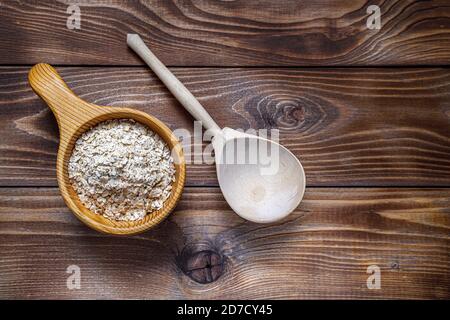 Tasse en bois et cuillère avec flocons d'avoine. Le concept de saine alimentation. Texture du bois. Mise en page à plat. Copier l'espace Banque D'Images