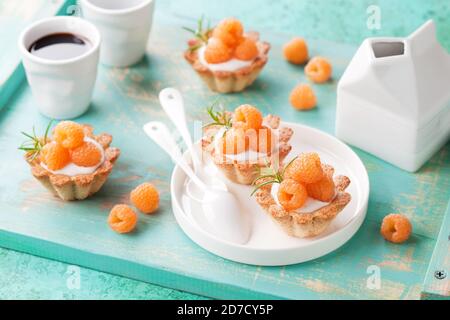 Tartelettes à la farine d'amandes avec crème anglaise et framboises jaunes fraîches, sélectif Banque D'Images