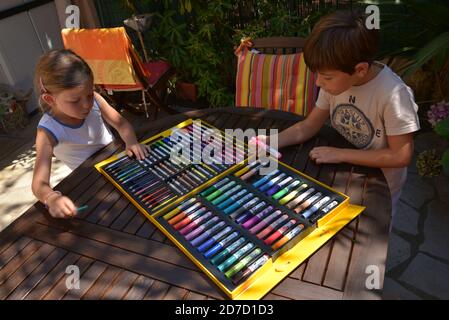 Frère et soeur dessin avec des marqueurs de couleur sur la terrasse  Banque D'Images