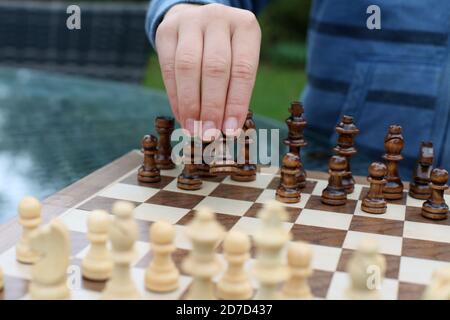 Enfant jouant aux échecs à l'extérieur, main se déplaçant sur la pièce de pion Banque D'Images