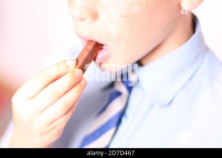 Enfant mangeant Quality Street Toffee chocolat aux doigts doux, gros plan Banque D'Images