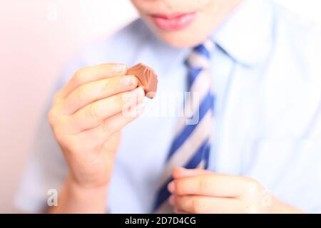 Enfant mangeant Quality Street Green Triangle chocolat doux, gros plan Banque D'Images