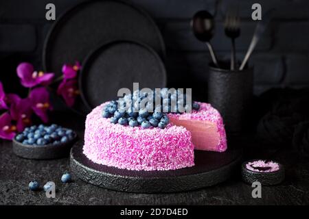 Gâteau à la crêpe maison avec crème de noix de coco rose pitahaya et bleuets frais sur fond noir, concentré sélectif Banque D'Images