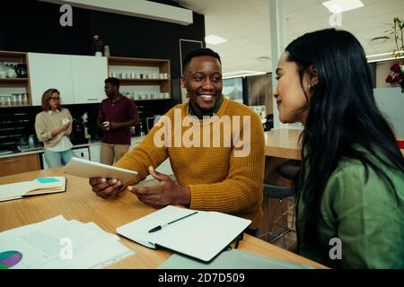 Homme d'affaires de race mixte souriant à la femme entrepreneur livrer avec succès idées de nouveau projet avant la réunion Banque D'Images