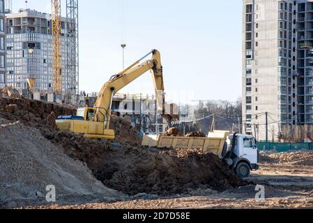 Pelle hydraulique creusant du sable et chargeant dans un tombereau à benne basculante sur le chantier de construction. La pelle rétro creuse le sol, fondement de la construction d'un nouveau résidentiel Banque D'Images