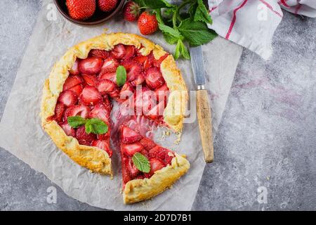 Galette avec fraise sur fond de pierre en béton gris. Galette végétarienne aux fruits rouges, décorée de fraises fraîches en tranches et de menthe. Suppr Banque D'Images