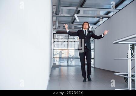 Projection de papier dans l'air. Portrait du beau jeune homme d'affaires en costume noir et cravate Banque D'Images
