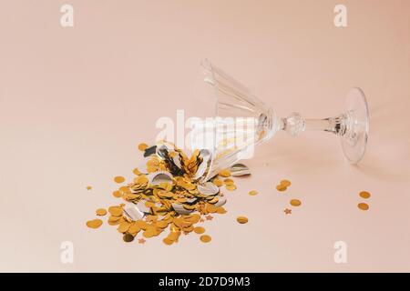 Verre à vin avec des sparkles d'or ou confetti sur fond rose. Concept de célébration. Banque D'Images