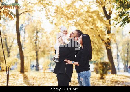Famille gaie s'amuser avec leur enfant dans beau parc d'automne Banque D'Images