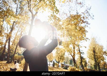 Belle lumière du soleil. Père en vêtements décontractés avec son enfant est dans le beau parc d'automne Banque D'Images