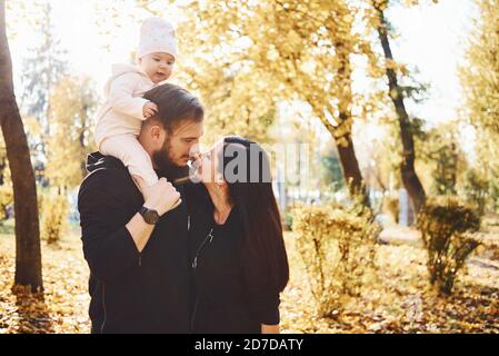 Famille gaie s'amuser avec leur enfant dans beau parc d'automne Banque D'Images