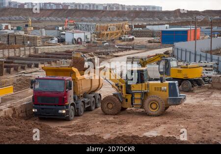 Le chargeur avant sur roues charge du sable dans le tombereau à benne basculante au niveau du chantier Banque D'Images