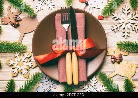 Vue de dessus de la coutellerie et la plaque sur fond de bois de fête. Nouvelle Année repas de famille concept. Sapin et décorations de Noël. Banque D'Images