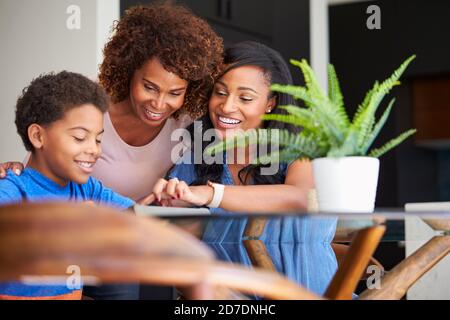 Grand-mère avec mère aidant petit-fils à faire le travail à domicile sur le numérique Tablette Banque D'Images