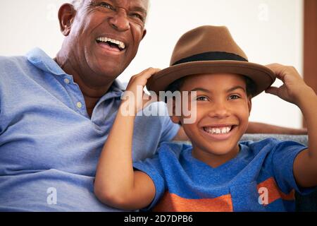 Grand-père et petit-fils afro-américains famille assis sur un canapé avec Garçon portant un chapeau Banque D'Images