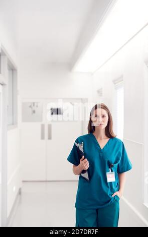 Portrait d'une femme médecin portant des exfoliants debout dans le couloir de l'hôpital Tenir le presse-papiers Banque D'Images